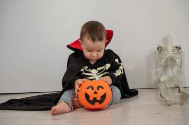 Beyaz arka planda şeker sepeti tutan Dracula Cadılar Bayramı kostümlü beyaz tatlı çocuk.