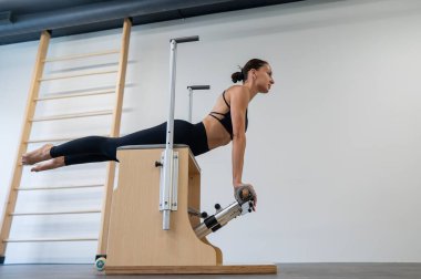 Beyaz kadın klasik sandalyede pilates yapıyor.