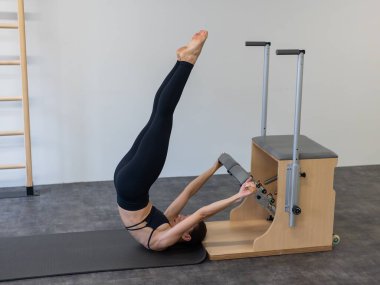 Beyaz kadın klasik sandalyede pilates yapıyor.