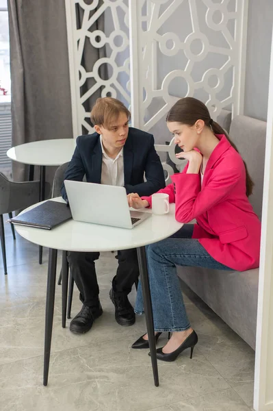 Meslektaşlar dizüstü bilgisayarda oturup iş konuşuyorlar.