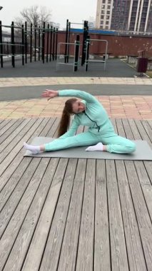Genç bir kadın dışarıda yoga yapıyor.