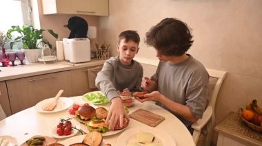 İki genç kardeş evde hamburger pişiriyor.