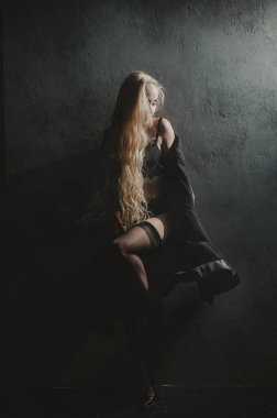 Uzun saçlı sarışın kadın iç çamaşırlarıyla poz veriyor.