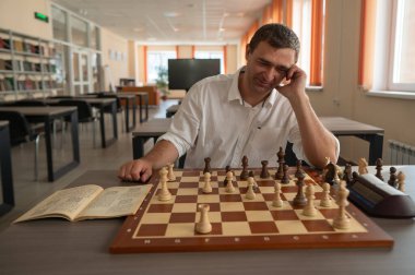 Orta yaşlı beyaz adam satranç oynuyor.