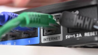 Bir kadın internet portundan yönlendiriciyle kablo çekiyor.