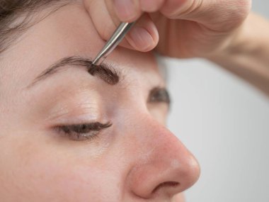 Beyaz kadın kaş boyama prosedürü uyguluyor.