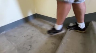 Bir adam merdivenlerden iniyor. Bacaklarını yakın çekim.