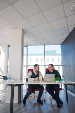 İki beyaz adam bir masada oturup iş tartışıyorlar.