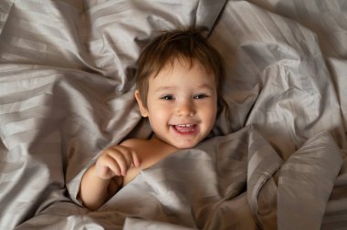 Beyaz tenli şirin bir çocuğun yatakta yatışının üst görüntüsü.