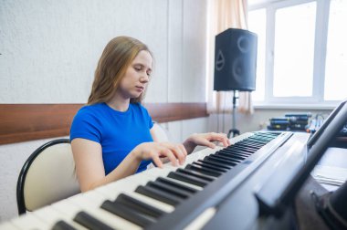 Beyaz kadın elektrikli piyano çalıyor.