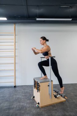 Beyaz kadın klasik sandalyede pilates yapıyor.
