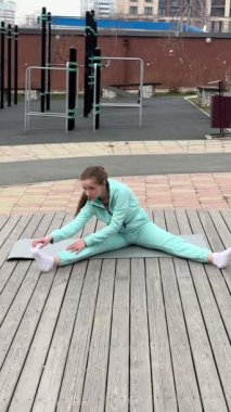 Genç bir kadın dışarıda yoga yapıyor.