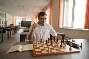 Orta yaşlı beyaz adam satranç oynuyor.