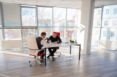 Bir ofiste pazarlık yapan iki beyaz adam.