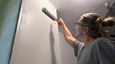 Kafkas kadın silindirle duvar boyuyor.