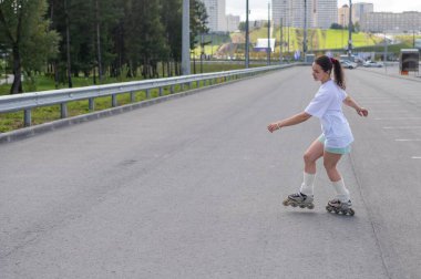 Beyaz kadın yolda hızla paten kayıyor.