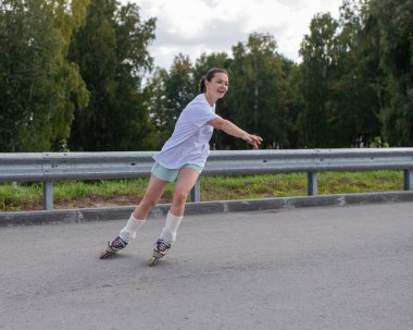 Beyaz kadın yolda hızla paten kayıyor.