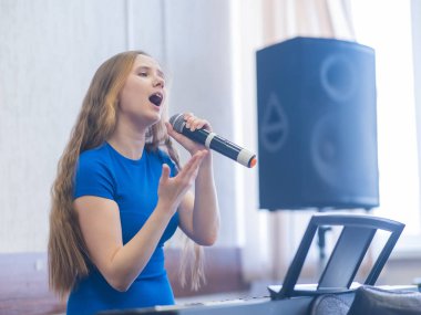 Beyaz kadın mikrofona şarkı söylüyor.