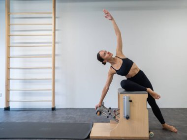 Beyaz kadın klasik sandalyede pilates yapıyor.