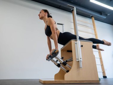 Beyaz kadın klasik sandalyede pilates yapıyor.