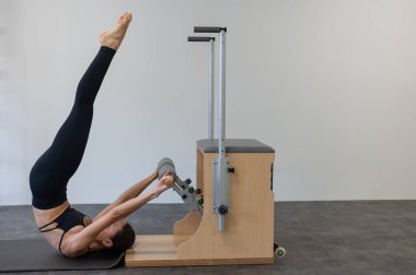 Beyaz kadın klasik sandalyede pilates yapıyor.