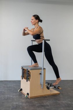Beyaz kadın klasik sandalyede pilates yapıyor.