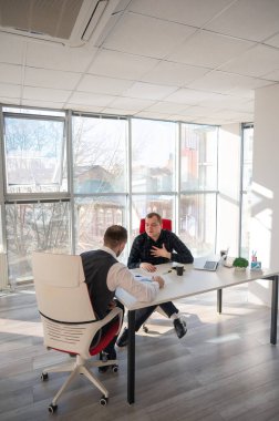 Bir ofiste pazarlık yapan iki beyaz adam.