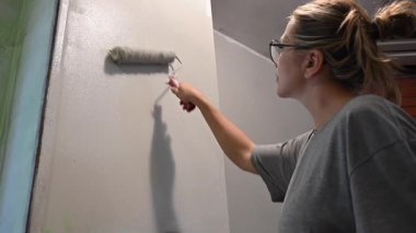 Kafkas kadın silindirle duvar boyuyor.