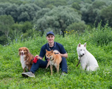 Beyaz bir adam üç köpekle yürür. Köpek gezdirici