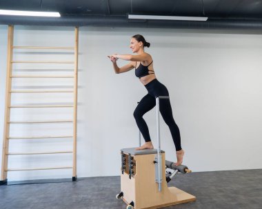 Beyaz kadın klasik sandalyede pilates yapıyor.