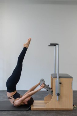 Beyaz kadın klasik sandalyede pilates yapıyor.