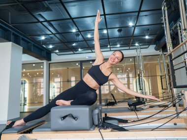 Kafkasyalı kadın yenilikçi makinede yan büküş yapıyor.