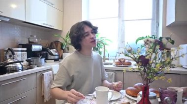 Orta yaşlı beyaz bir kadın oğluyla yemek yiyor.