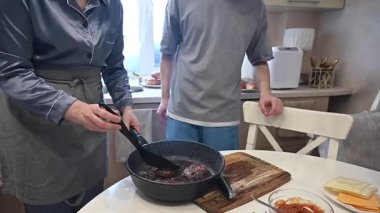 Bir kadın pirzola kızartır. Kadınların ellerinin yakınına.