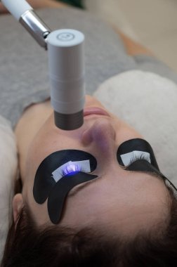 Kirpik uzatma prosedüründen geçen bir kadın ultraviyole lamba kullanıyor.