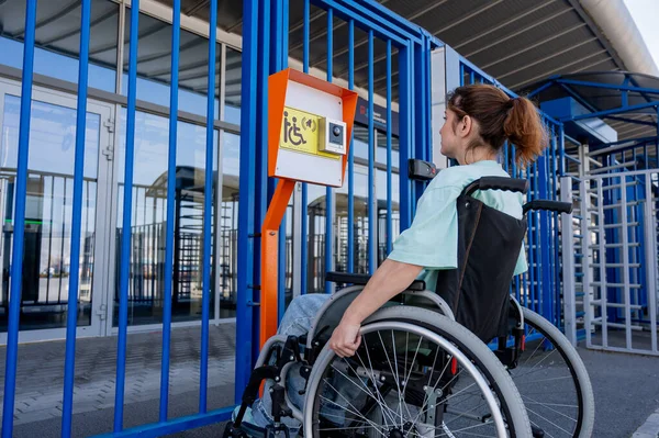 Tekerlekli sandalyedeki bir kadın dokunmaya duyarlı körler için yardım düğmesi kullanır..