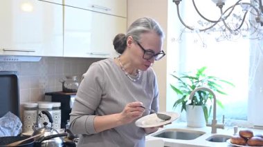 Orta yaşlı beyaz bir kadın oğluyla yemek yiyor.