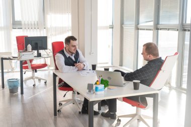 Bir ofiste pazarlık yapan iki beyaz adam.