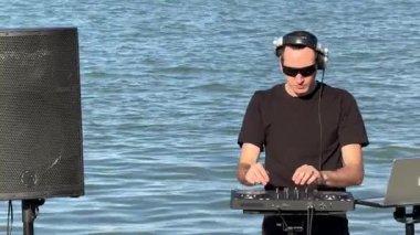Beyaz adam plajda DJ olarak çalışıyor.