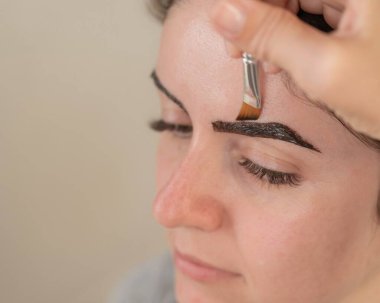 Beyaz kadın kaş boyama prosedürü uyguluyor.