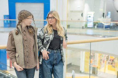 Bir anne ve genç kızı bir alışveriş merkezinde yürüyorlar.