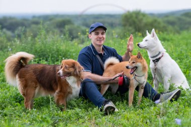 Beyaz bir adam üç köpekle yürür. Köpek gezdirici