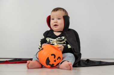 Beyaz arka planda şeker sepeti tutan Dracula Cadılar Bayramı kostümlü beyaz tatlı çocuk.