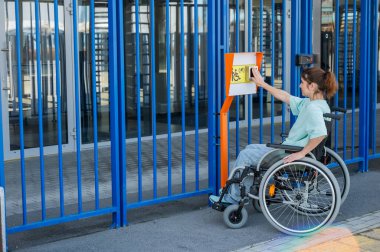 Tekerlekli sandalyedeki bir kadın dokunmaya duyarlı körler için yardım düğmesi kullanır..