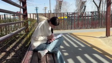 Açık havada kalemle çizim yapan beyaz bir kadın.