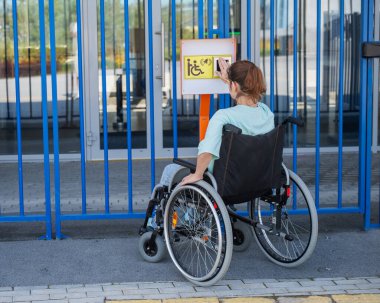 Tekerlekli sandalyedeki bir kadın dokunmaya duyarlı körler için yardım düğmesi kullanır..