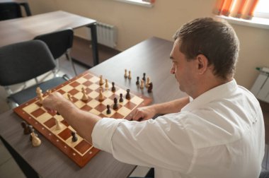 Beyaz adam satranç hamlesi düşünüyor.