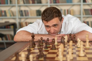 Beyaz adam satranç hamlesi düşünüyor.