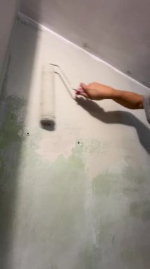 Kafkas kadın silindirle duvar boyuyor.