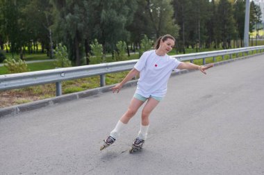 Beyaz kadın yolda hızla paten kayıyor.